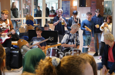 Eine Schülerband mit Trompeten, E-Gitarre, E-Bass und Schlagzeug spielt in der Pausenhalle